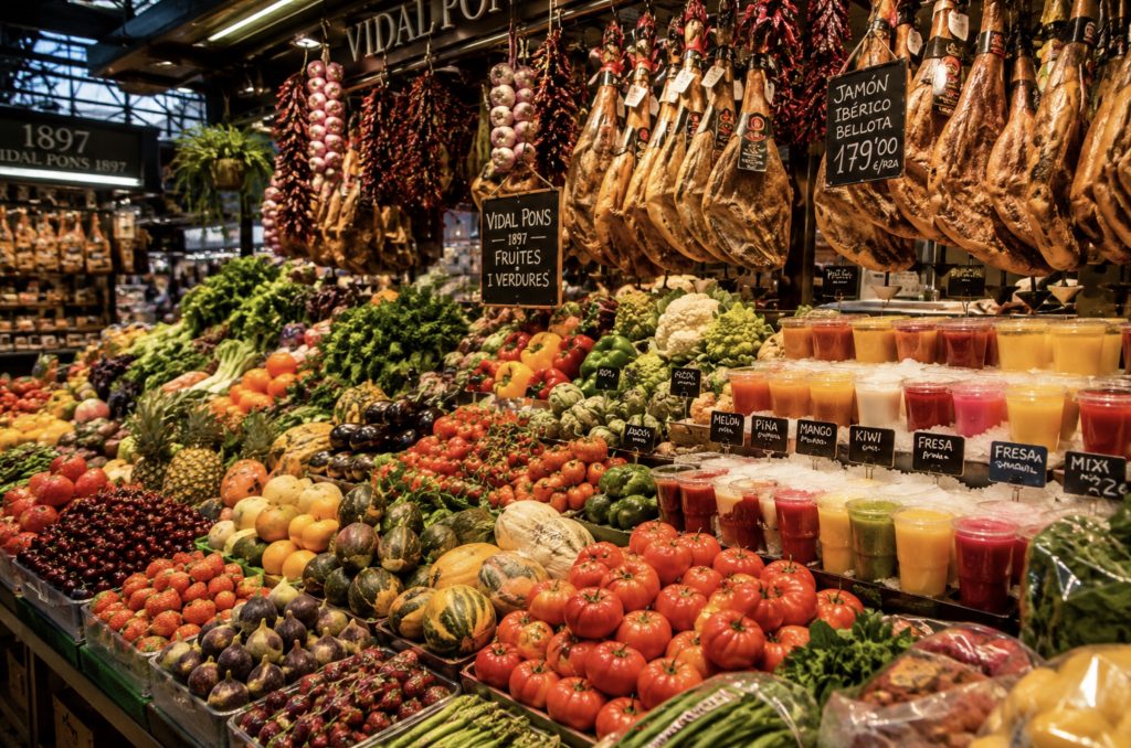 Барвисті прилавки зі свіжими фруктами та продуктами на ринку Ла Бокерія в Барселоні